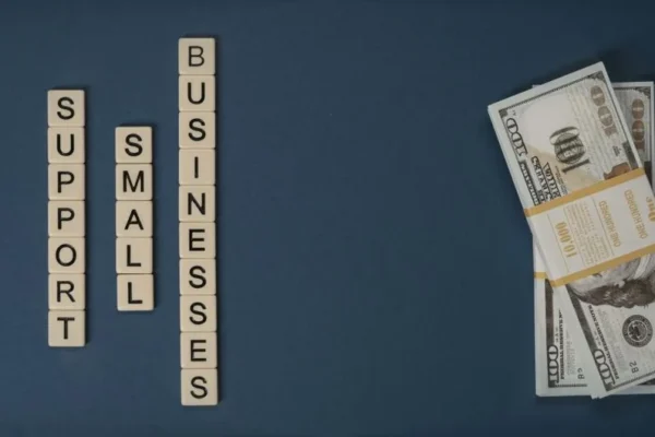Conceptual image of supporting small businesses with financial resources using money and letter tiles.