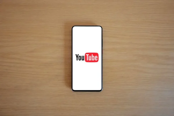 Top view of smartphone displaying YouTube logo on a wooden surface, showcasing modern technology.