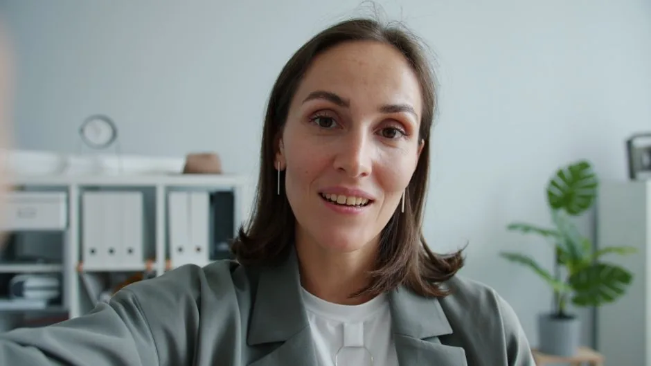 Close-up of a confident woman in an office environment, smiling at the camera.