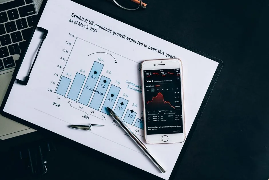 A smartphone displaying stock data rests on a financial report graph.