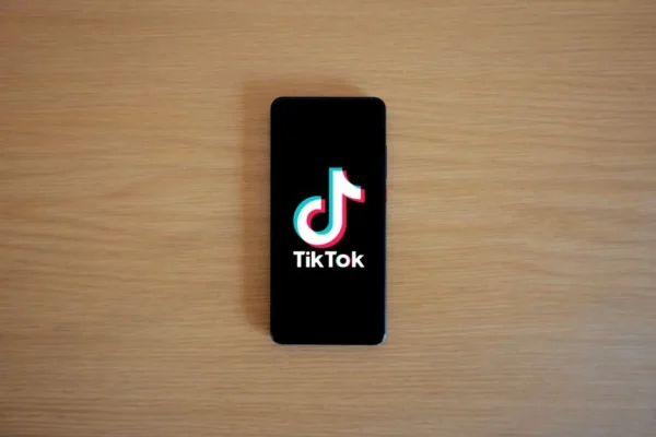 Smartphone with TikTok app displayed on black screen against a wooden background.