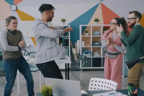 A group of four diverse colleagues celebrating a success in a creative office space.