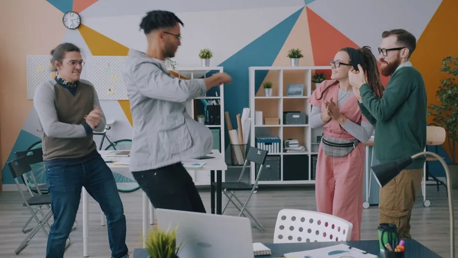 A group of four diverse colleagues celebrating a success in a creative office space.